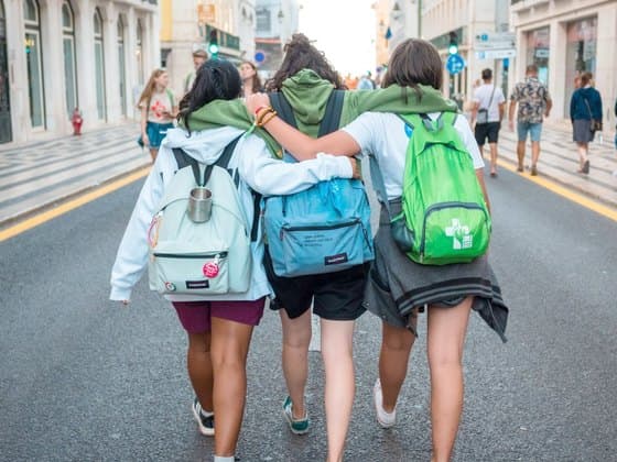 Three friends walking off together, arms around each other