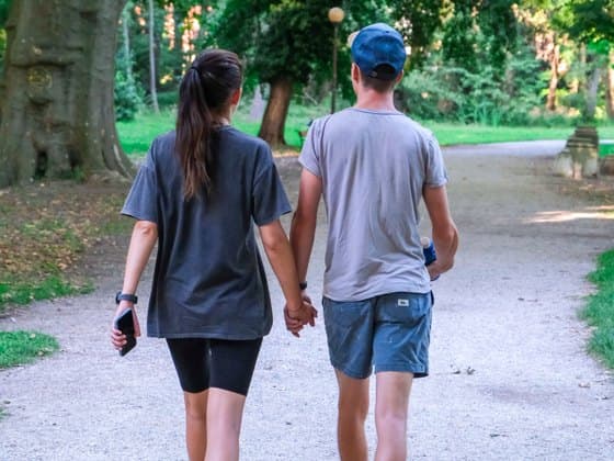 Two friends walking hand in hand through a park